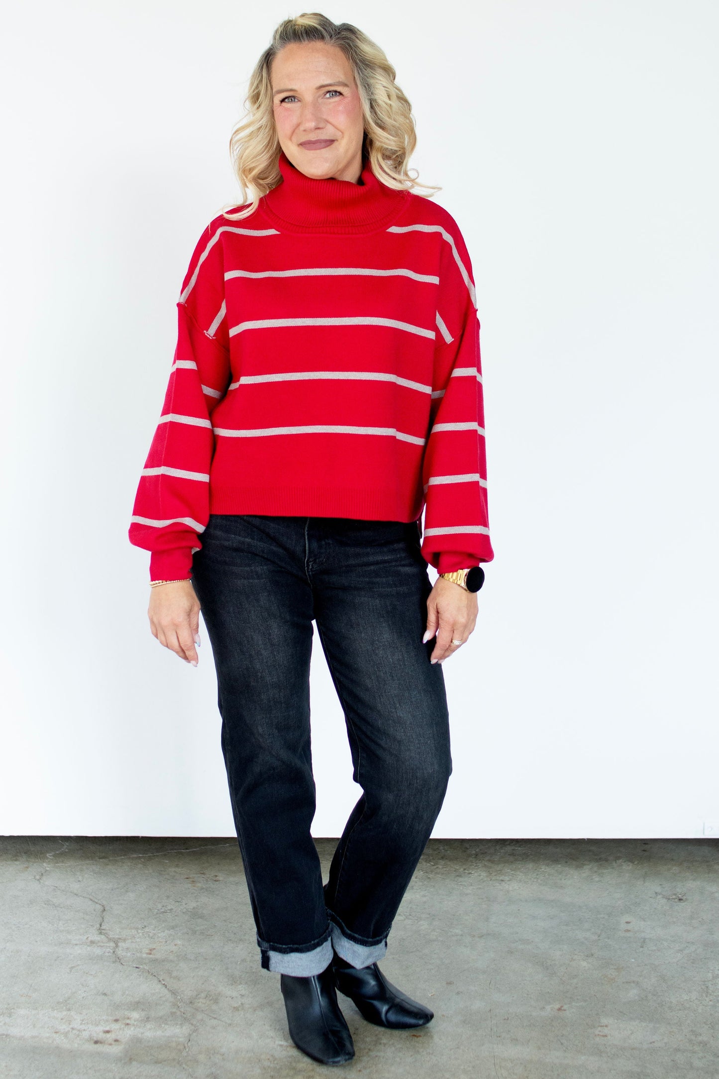 Person wearing a red and white striped sweater and dark jeans against a white background